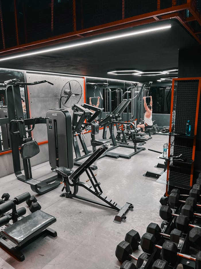Spacious indoor gym with weight machines and a person working out.